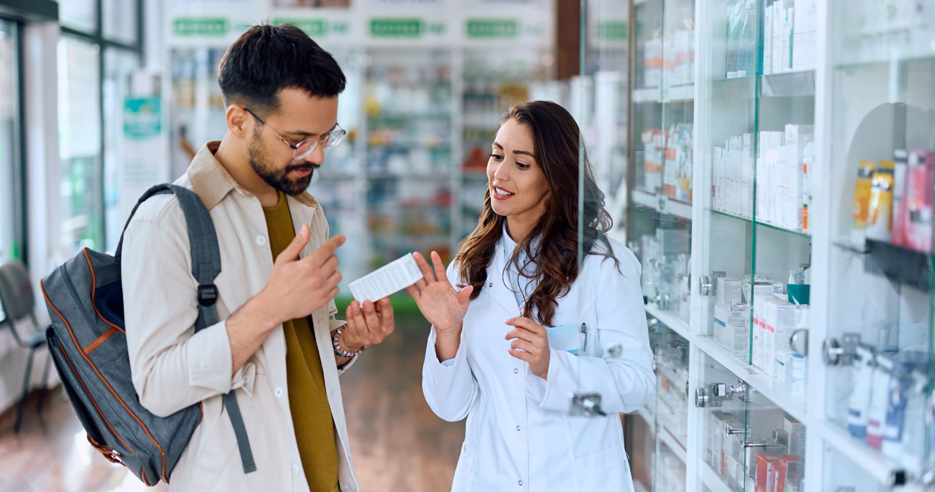 Mężczyzna konsultujący wybór dermokosmetyku z farmaceutką w aptece.